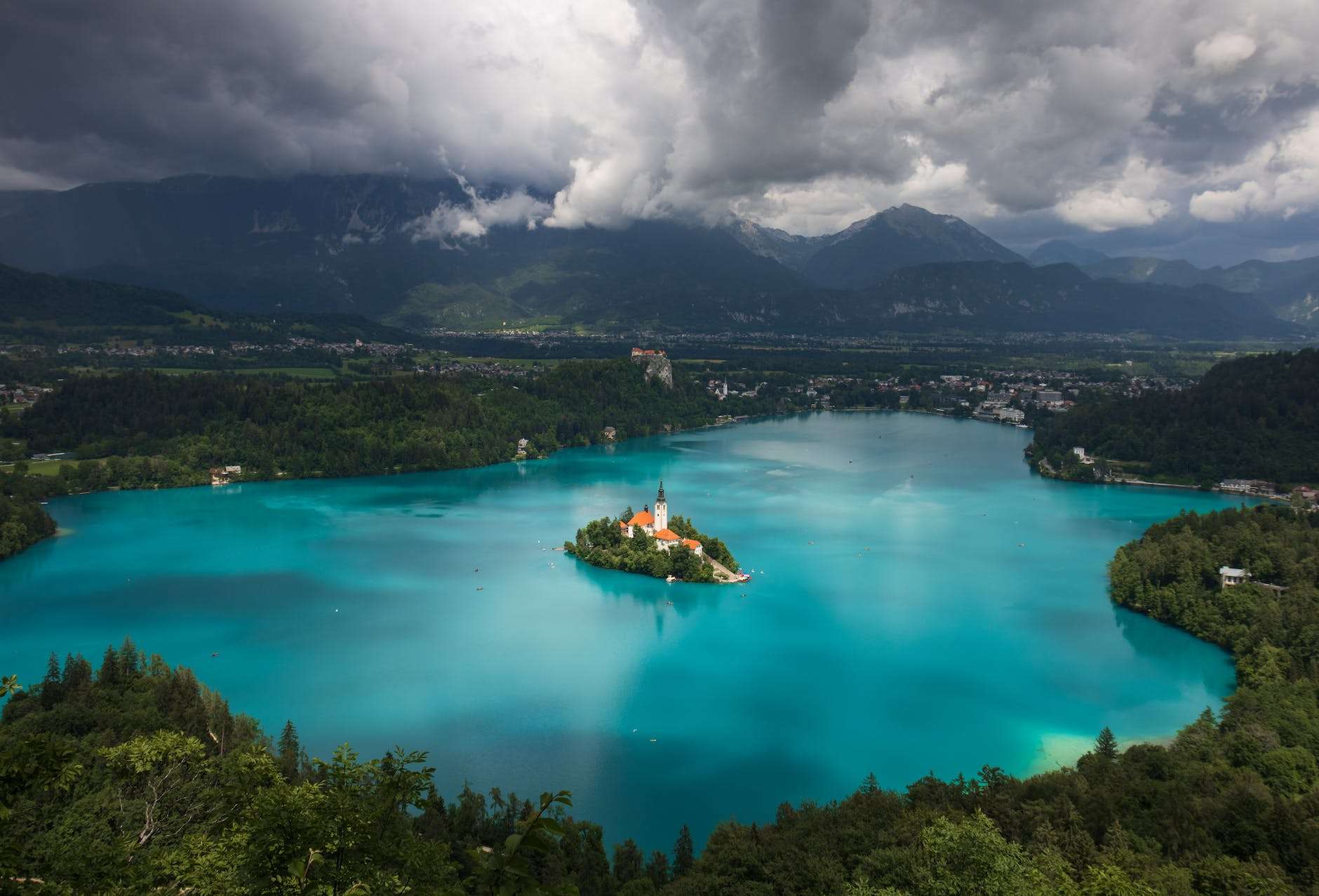 the lake bled is surrounded by green mountains